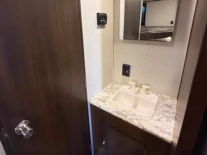 Inside an RV rental: a compact bathroom vanity with sink, mirror, and thermostat, offering essential amenities.. Keystone RV Springdale 2021