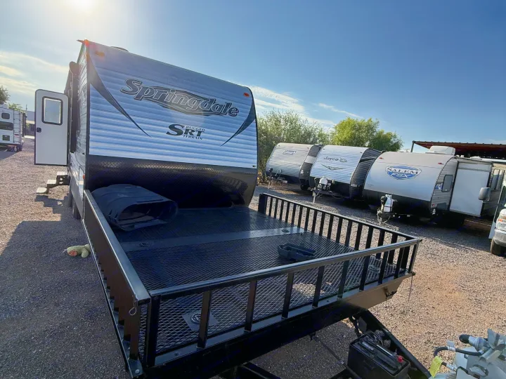 A Springdale SRT travel trailer with a front cargo deck sits on a sunny lot among other RVs, ready for your next RV rental adventure.. Keystone RV Springdale SRT 2016