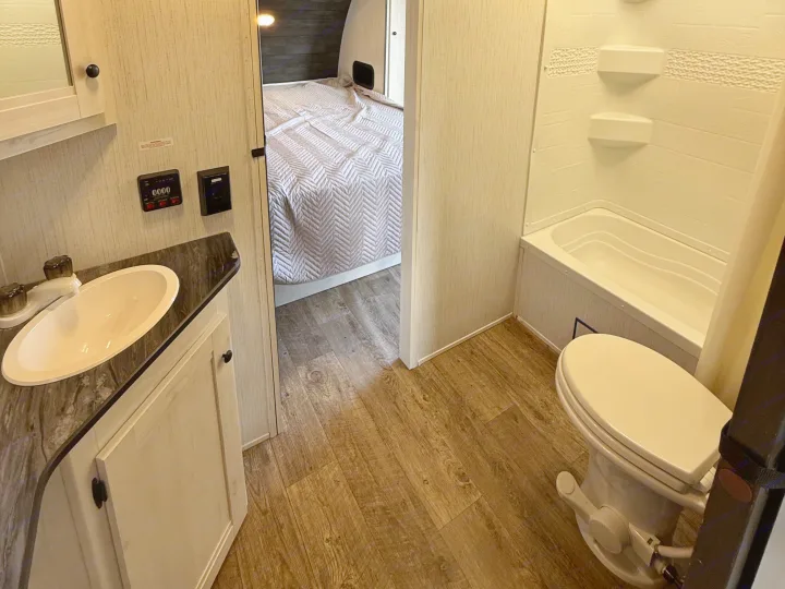RV rental: Modern compact interior with a full bathroom (sink, toilet, shower), vanity, and a glimpse of the bedroom.. Heartland RVs Trail Runner 2022