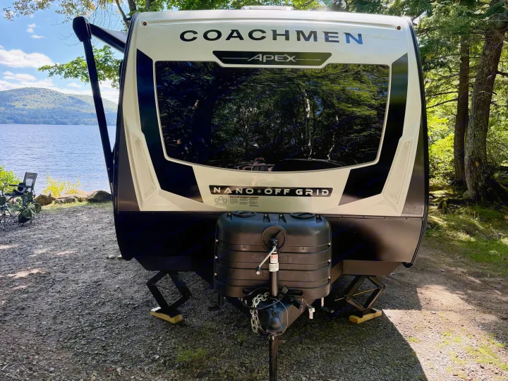 A Coachmen Apex Nano Off Grid RV rental parked lakeside with stabilizers down, ready for nature camping by a scenic lake.. Coachmen Apex Nano 2026