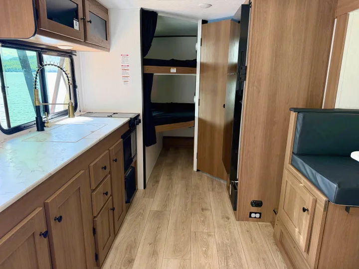 Spacious RV rental interior featuring a kitchenette, dinette, bunk beds, and a scenic window view for your next adventure.. Coachmen Apex Nano 2026
