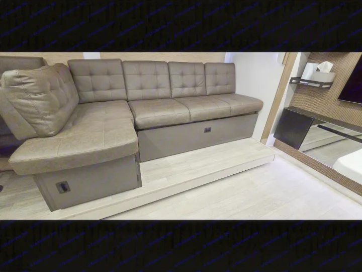 Modern L-shaped dinette sofa with storage and step in this RV rental, offering comfortable seating and smart space use.. Forest River Wildwood X-Lite 2025