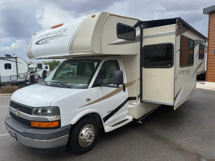This white and tan Class C RV rental with an extended slide-out is parked outdoors, ready for adventure.. Coachmen Leprechaun 240FS 2018