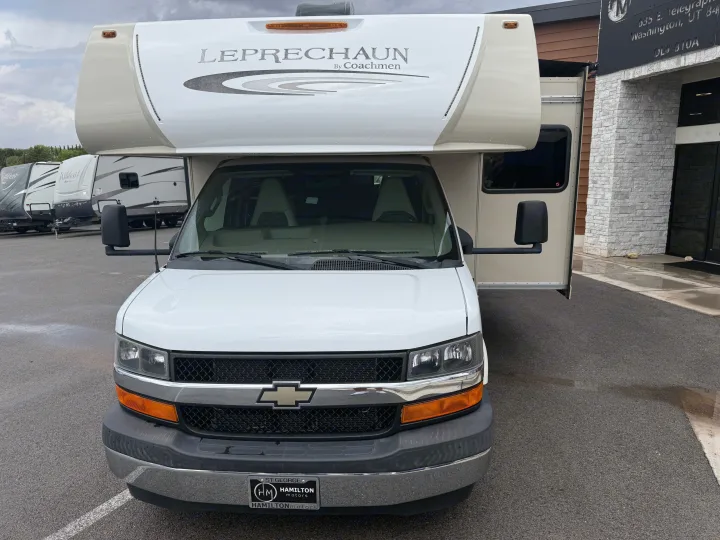 White Coachmen Leprechaun Class C RV for rv rental, parked at a dealership with other travel trailers under cloudy skies.. Coachmen Leprechaun 240FS 2018