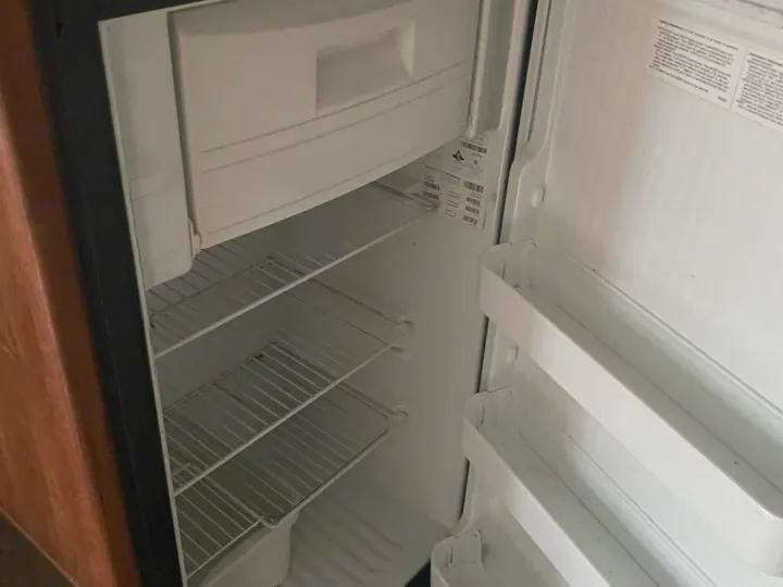 Inside an empty Norcold refrigerator in an RV rental, showing its wire shelves and door storage. Ready for your trip!. Jayco Jay Feather Ultra Lite 2012