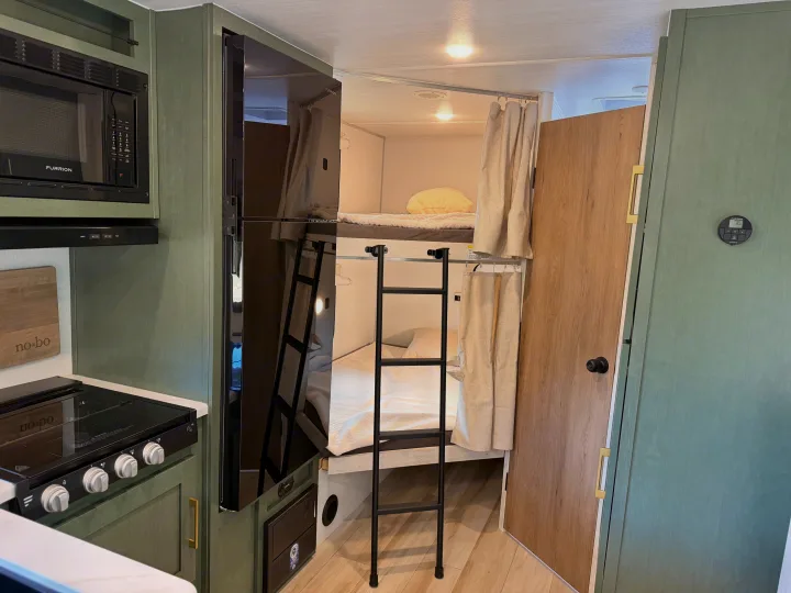 RV rental interior: cozy bunk beds, a compact kitchen with microwave & stove, and a refrigerator, perfect for family travel.. No Boundaries 20 2026