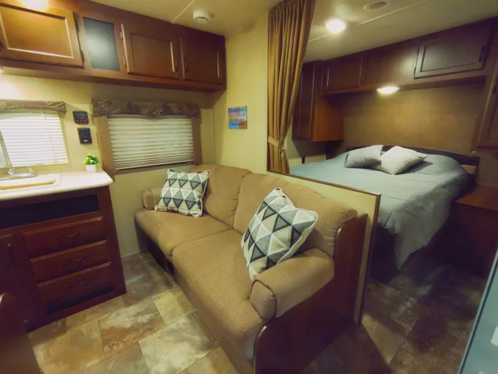 RV rental interior with a welcoming living room, kitchen counter, overhead cabinets, and a comfortable bed in the back.. Jayco Jay Flight Swift 2014