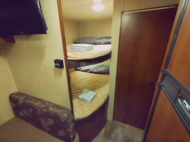 Inside an rv rental: features cozy bunk beds, a TV, and compact living space, ready for your next adventure.. Jayco Jay Flight Swift 2014