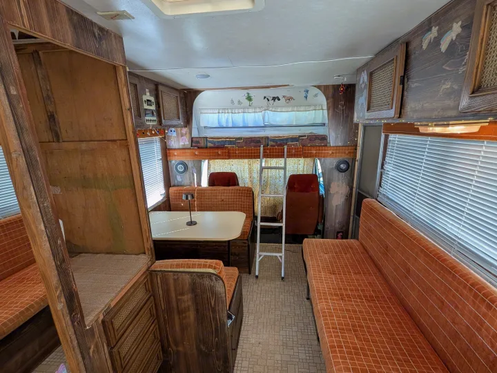 Cozy RV rental interior with a vintage feel, featuring a dining booth, overhead bunk, and plenty of seating.. Chevrolet Vanguard 1980