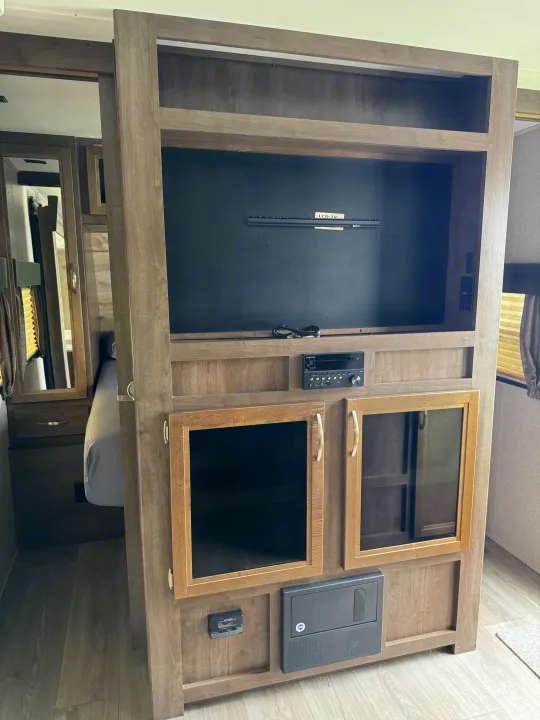 This RV rental's built-in entertainment center features a TV mount, stereo, and glass-front cabinets in a modern wood finish.. Dutchmen Coleman Light 2019