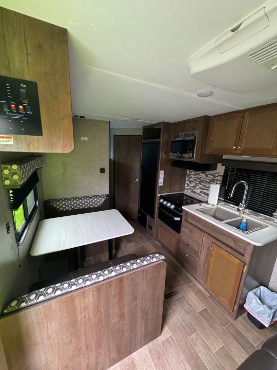 This inviting RV rental interior features a functional kitchen with appliances, a cozy dinette, and modern wood-look flooring.. Dutchmen Coleman Lantern LT 2020