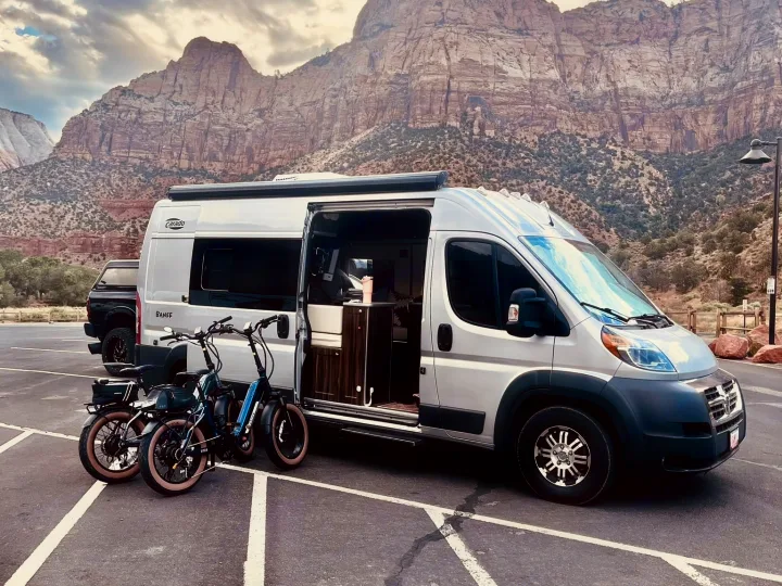 This RV rental, a silver camper van with e-bikes, is parked before majestic mountains, perfect for adventure.. Hymer Carado 2018