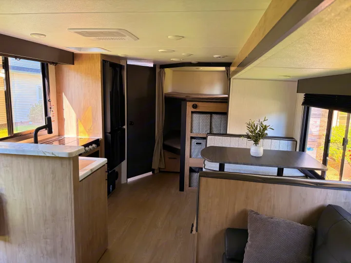 Bright and modern RV rental interior featuring a full kitchen, bunk beds, and dinette. Ideal for comfortable travel.. Forest River Campsite Reserve 2026