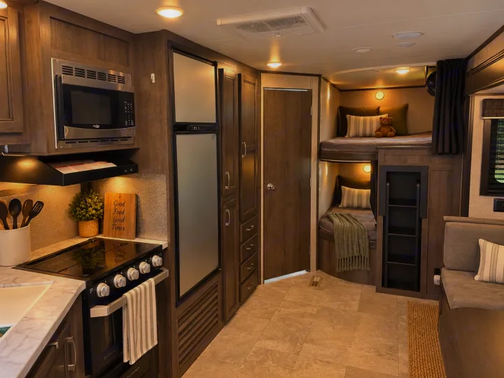 This RV rental interior showcases a full kitchen, cozy bunk beds, and a dining area, perfect for family adventures.. Jayco Jay Flight 2021