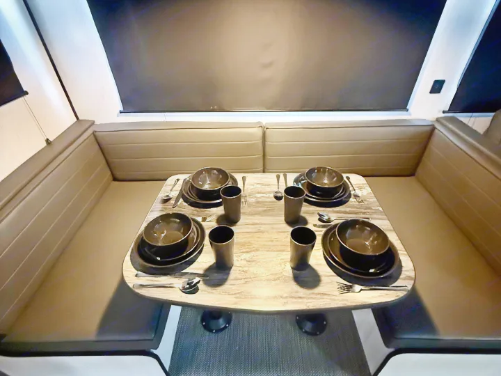 RV rental dinette with dark booth seating and a table set for four, featuring modern dark dishes and cups.. Heartland RVs Trail Runner 2022