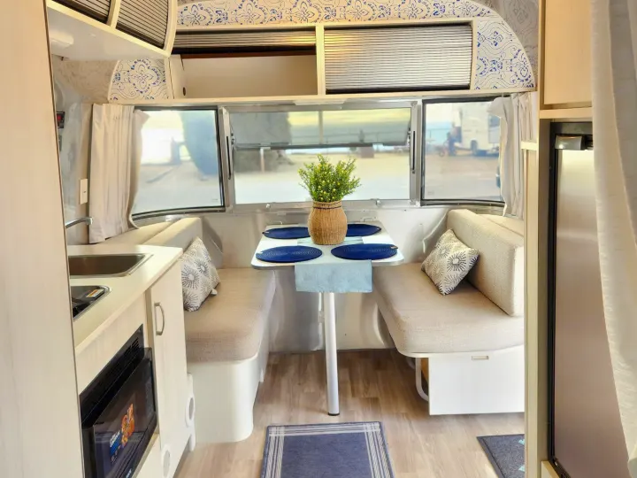 Experience comfort in this rv rental interior, featuring a bright dining area, compact kitchen, and chic decor for travel.. Airstream Bambi 2023