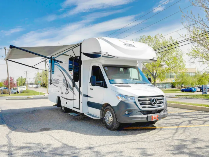 This white Mercedes-Benz RV rental, a Jayco Melbourne model, features an extended awning, parked on a sunny day.. Jayco Melbourne 2022