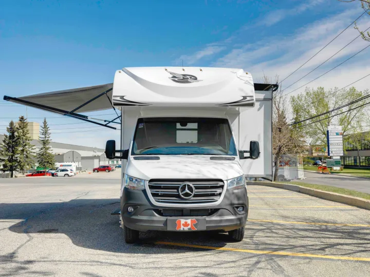 Front view of a white Mercedes-Benz Sprinter RV rental with an extended awning, parked in a lot. Ready for your trip!. Jayco Melbourne 2022