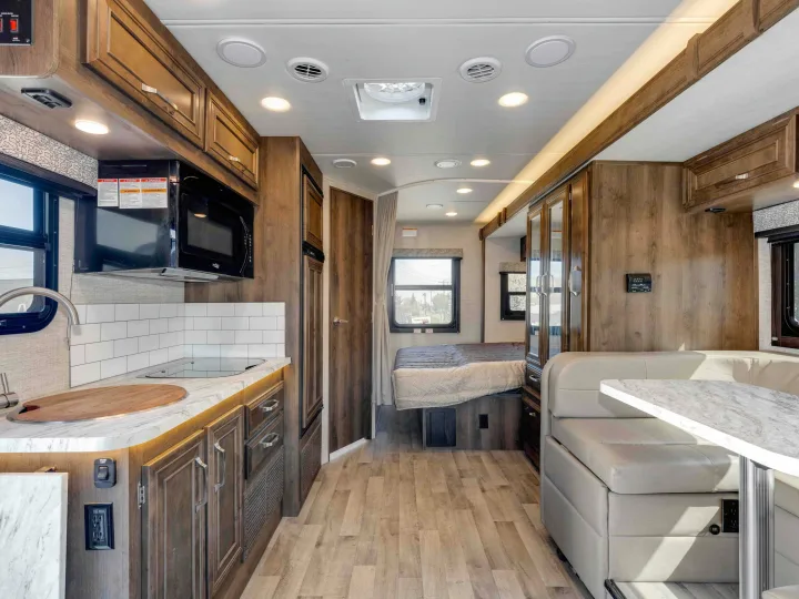 RV rental's inviting interior: modern kitchen, comfortable dinette, and cozy bedroom, all with wood finishes and bright lighting.. Jayco Melbourne 2022