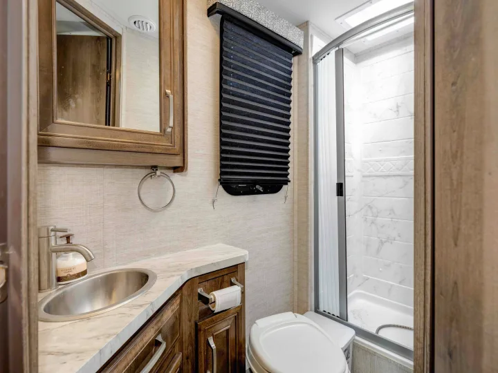 Compact RV rental bathroom with a vanity, sink, toilet, and glass-enclosed shower, offering practical amenities.. Jayco Melbourne 2022