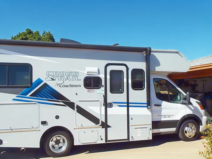 This gray Coachmen Cross Trail RV rental is parked outside under a clear blue sky, ready for adventure.. Coachmen Ford Transit 2023