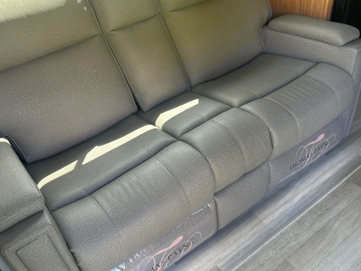 New gray textured Thomas Payne Collection sofa, still partially wrapped, in an RV rental. Comfort for your travels.. Keystone RV Passport SL 2025