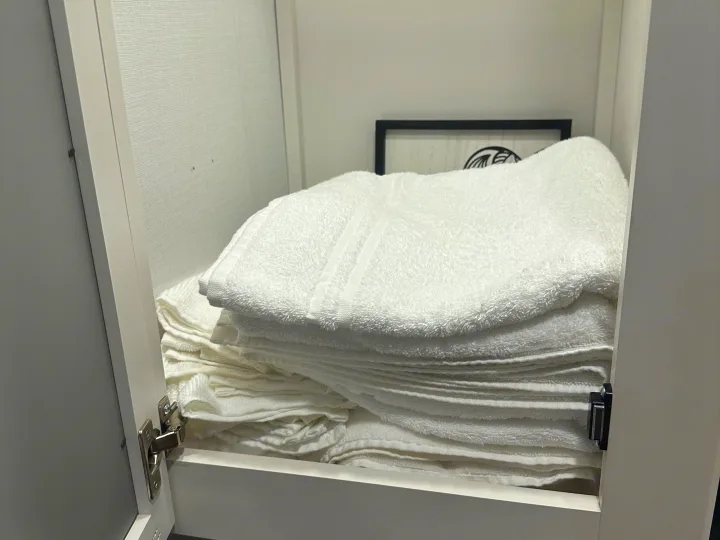 Neatly folded white towels in an RV rental cabinet. Essential amenities for a comfortable trip.. Keystone RV Passport SL 2025