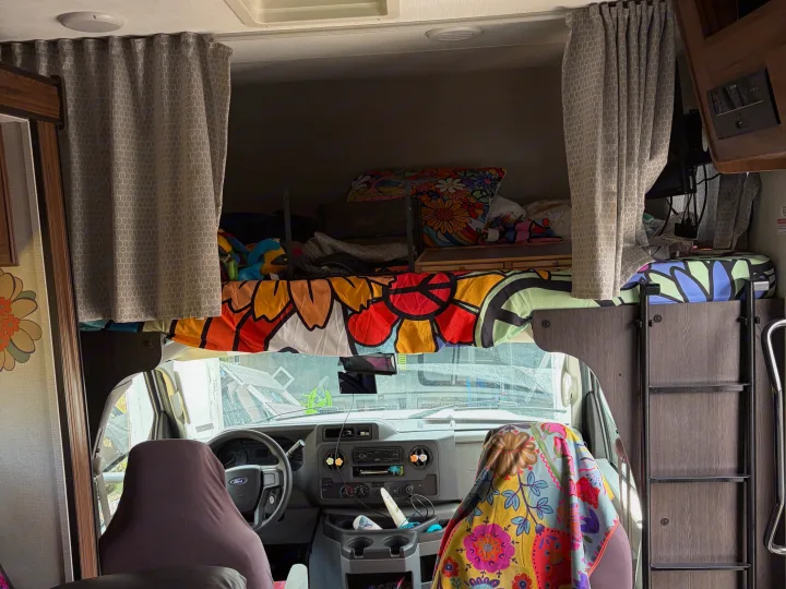 RV rental interior: colorful overhead bunk, front cab, and cozy living space with patterned flooring.. Forester LE 2022