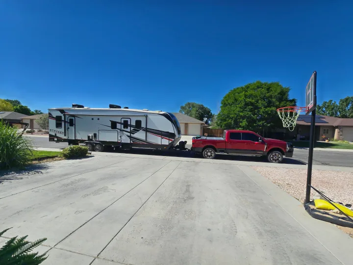 A red pickup truck is towing a Stryker travel trailer in a sunny driveway, ideal for an RV rental vacation.. Cruiser Rv Corp Stryker 2025