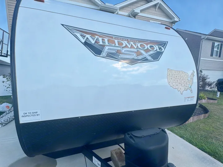 Front of a white Forest River Wildwood FSX travel trailer, ideal for an RV rental road trip. Features US map sticker.. Forest River Wildwood FSX 2023