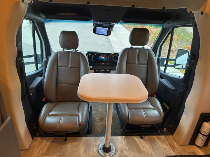 RV rental interior: front cabin with swiveling seats facing a small table, ready for dining or work on the road.. Thor Quantum 2023