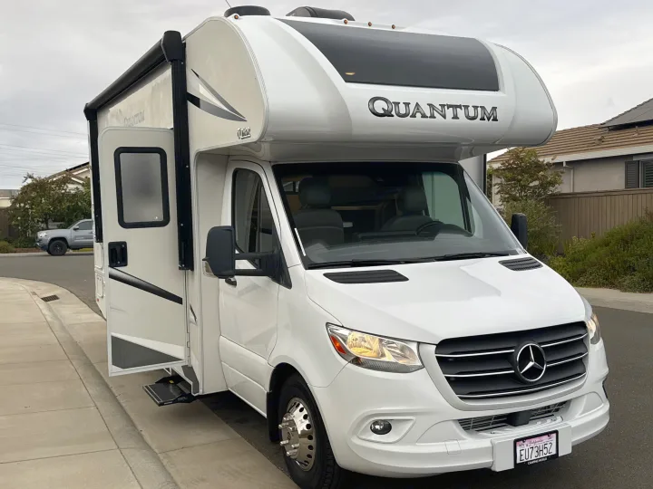 White Thor Quantum RV rental (Mercedes-Benz chassis) parked on a street with its door open and step extended.. Thor Quantum 2023