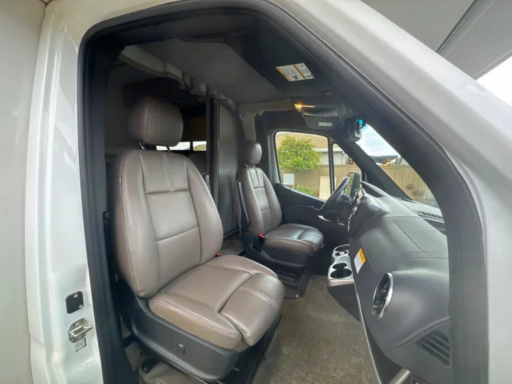 Spacious RV rental front cabin showcasing comfortable gray leather seats, dashboard, and steering wheel.. Thor Quantum 2023