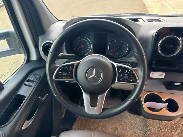 Detailed interior of an RV rental: Mercedes-Benz Sprinter steering wheel, dashboard, and driver controls. Ready for adventure.. Thor Quantum 2023