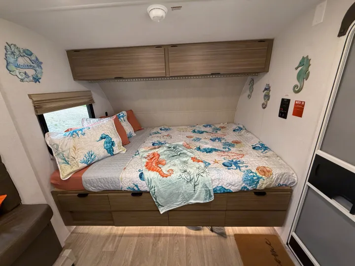 Cozy ocean-themed RV rental bedroom with a bed, under-bed drawers, overhead cabinets, and nautical decor.. Forest River Salem 2026