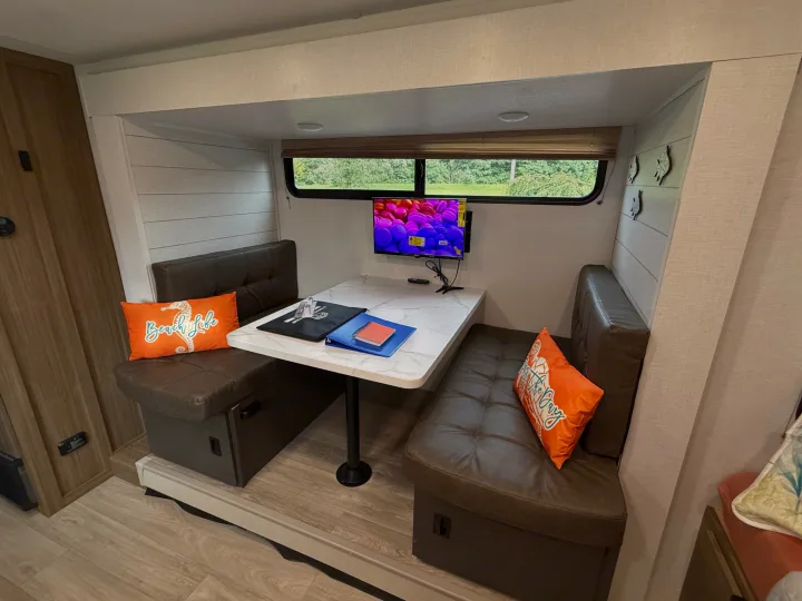Inside an RV rental: a dinette with two cushioned benches, a table, TV, and scenic window views through large windows.. Forest River Salem 2026