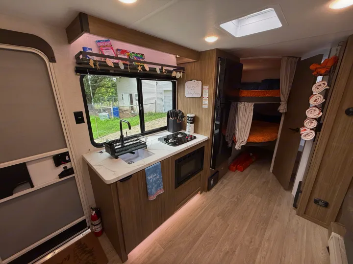 An inviting rv rental interior: kitchenette with sink, stove, microwave, plus cozy bunk beds & a welcome sign.. Forest River Salem 2026