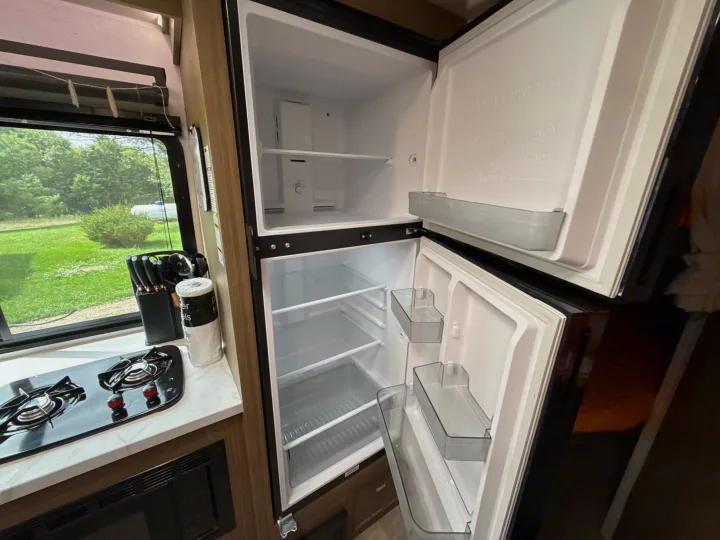 Inside an RV rental: a compact kitchen featuring an open refrigerator, two-burner stove, and microwave.. Forest River Salem 2026