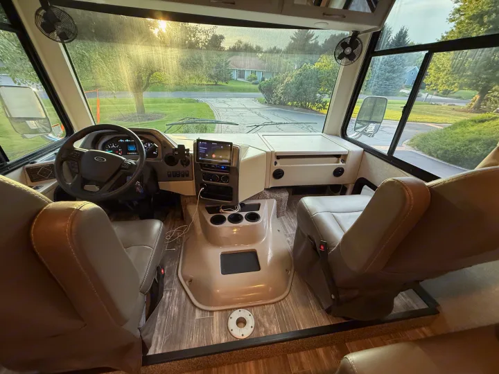 Spacious RV rental driving area: cockpit with dashboard, infotainment, comfortable seats, and a bright view of the road ahead.. Thor Hurricane 2022