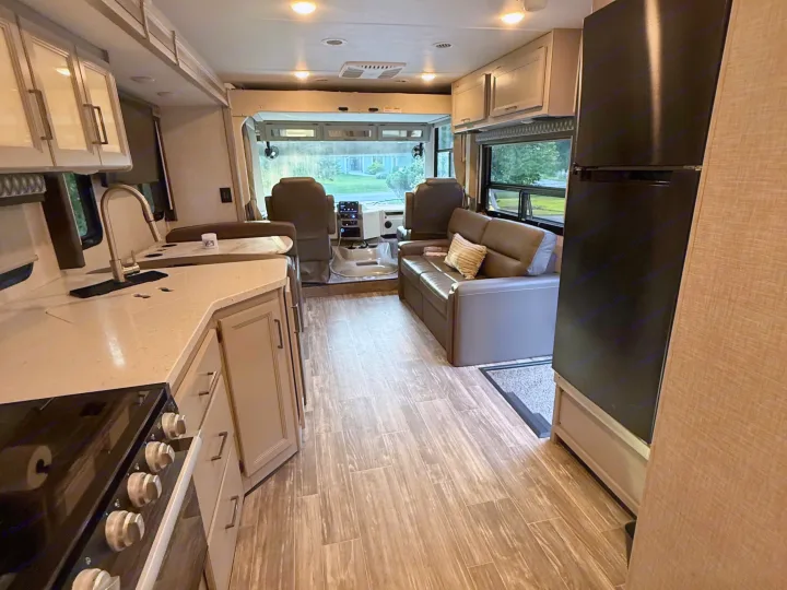 Spacious rv rental interior showcasing a full kitchen, living area with sofa, and the driver's cockpit. Ideal for road trips.. Thor Hurricane 2022