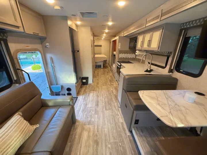 This RV rental offers a well-equipped kitchen, a comfortable dinette, and a cozy sofa, with a pool view from the door.. Thor Hurricane 2022