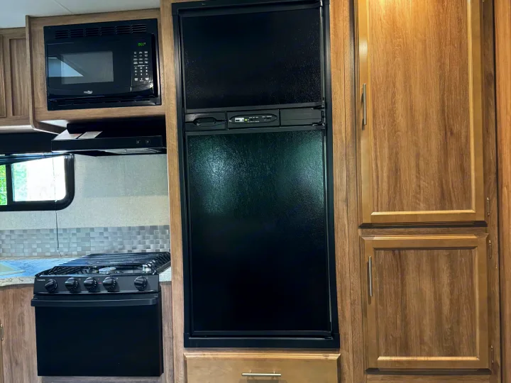 Explore this RV rental's compact kitchen, featuring a microwave, gas stovetop, and refrigerator for all your cooking needs.. Jayco Jay Feather 2018