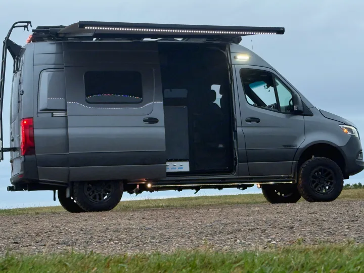 Customized Winnebago Sprinter rv rental, a camper van with bright LEDs, open door, and ladder, ready for adventure.. Winnebago Revel 2025
