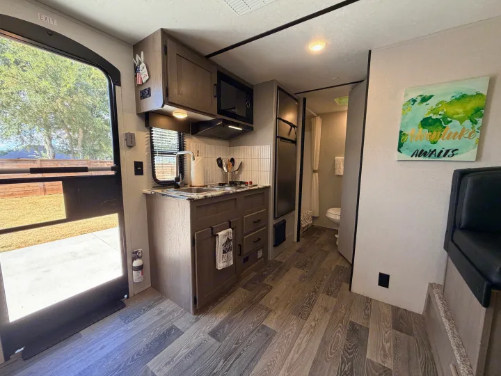 This inviting RV rental offers a functional kitchen, compact bathroom, and 'Adventure Awaits' decor. Step inside to begin your journey!. Keystone RV Hideout 2021