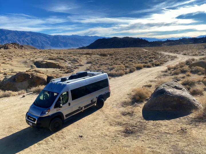 RV rental van on a winding desert dirt road with mountains under a blue sky, ideal for off-grid adventures.. Thor Sequence 2022