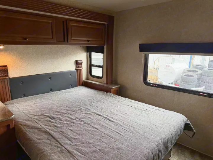 Spacious RV rental bedroom interior features a comfortable bed, wood cabinets, and two windows in this camper's cozy sleeping area.. Tioga Montara 2013