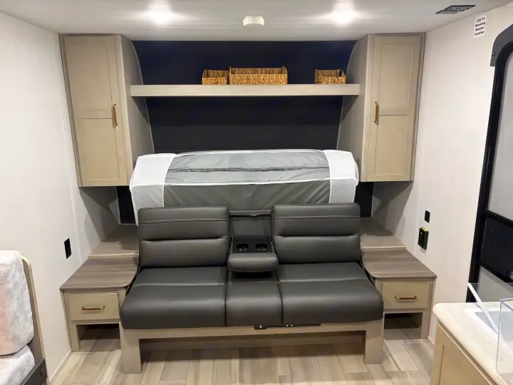 Cozy RV rental interior with a versatile sofa that converts to a bed, overhead storage, and bedside tables.. Keystone RV Springdale 2024