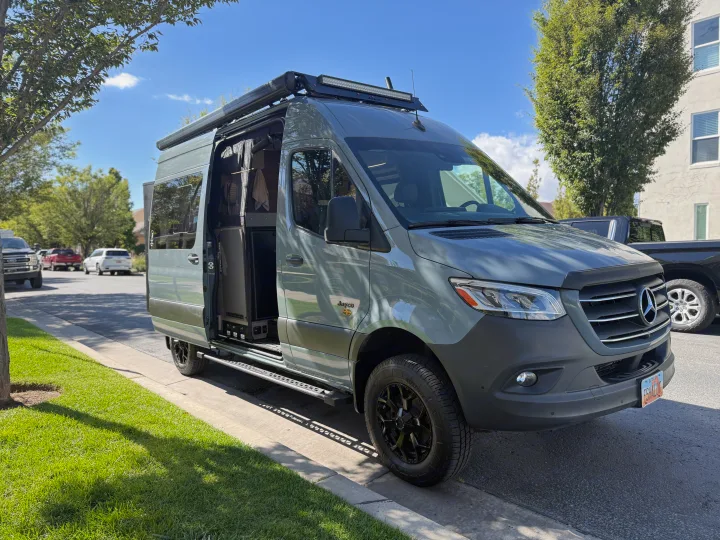 This custom grey Jayco Mercedes Sprinter camper van, perfect for rv rental, shows its open side door and inviting interior.. Jayco Terrain 2023