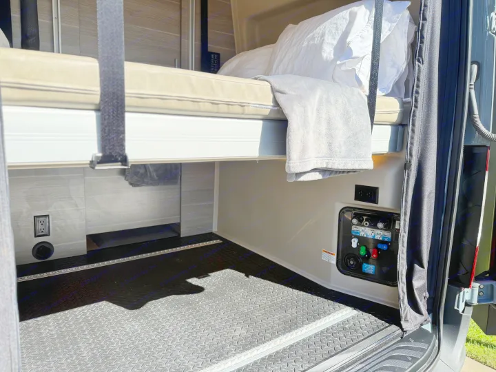 RV rental campervan interior: bunk bed, water utility panel, electrical outlet, and functional cargo area.. Jayco Terrain 2023