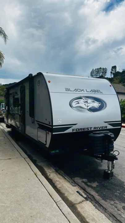This modern Forest River Black Label RV rental is parked curb-side under a cloudy sky, ready for your next adventure.. Forest River Cherokee Grey Wolf 2027